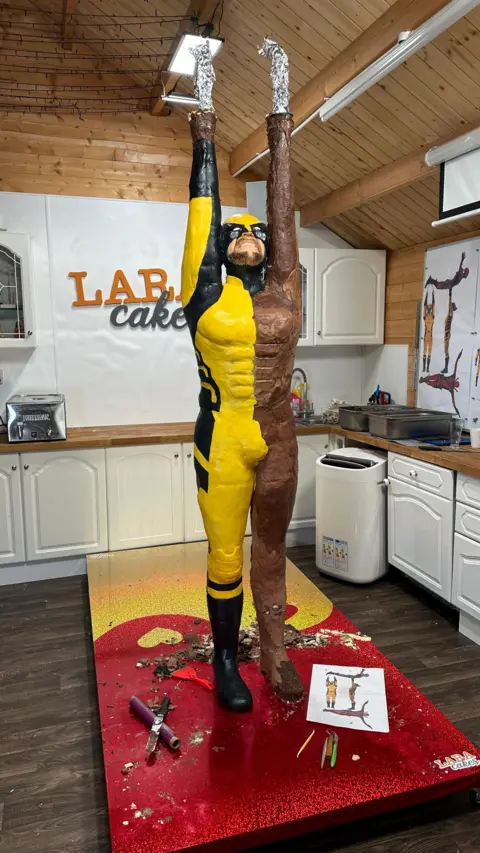 Lara Mason The Wolverine cake statue, half painted and decorated on the left side, but just covered in chocolate on the right