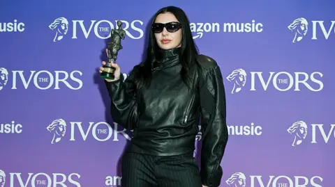 Charli XCX holds up her Ivor Novello Award