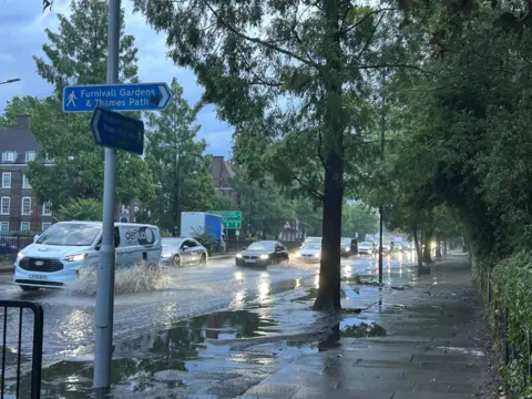 Marzy / Weather Watchers Cars drive through a flooded road in Hammersmith, London. 