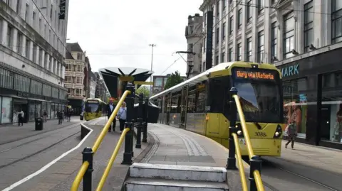 Two trams line up at the busy Market Street station on a cloudy day