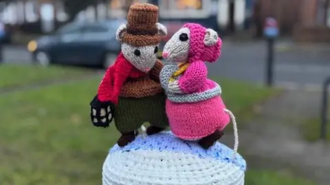 Haughton Ladies Who Knit Two colourful knitted characters from the Charles Dickens' novella, 'A Christmas Carol'. The characters are mice and sit as a bollard topper.