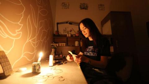 Puppet designer works in workshop in Kyiv by candlelight