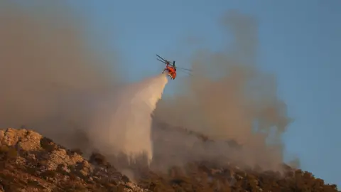 Reuters A firefighting helicopter drops water near Nea Makri, east of Athens