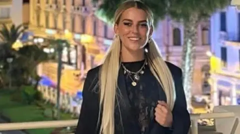 Cyane Panine has long blonde hair wearing a black top and smiling