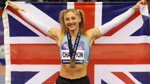 PA Media Great Britain's Molly Caudery celebrates after winning the final of the Women's Pole Vault on day one of the Novuna UK Athletics Indoor Championships at Utilita Arena, Birmingham. She holds up a union flag behind her.