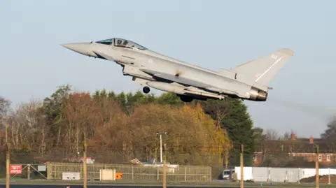 A Typhoon taking off from RAF Coningsby in Linconshire. The sky is blue.