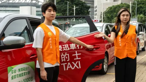 Polite Ambassadors are holding a taxi door open during a Publicity Campaign Launch Ceremony in Hong Kong, on June 5, 2024