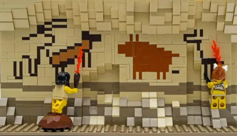 East Riding of Yorkshire Council Lego artwork depicting two yellow figures painting animals on the wall of a cave.