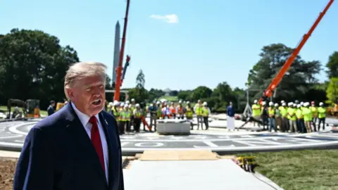 President Trump stands at the White House helipad construction site.