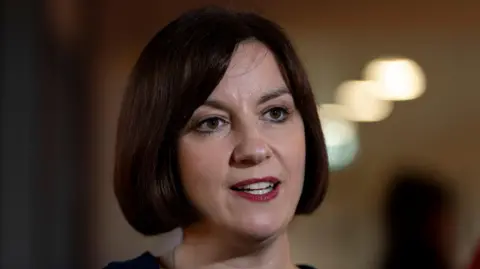 PA Media Bridget Phillipson gives a TV interview in a room. Her dark brown hair is in a bob style and she wears a dark top.