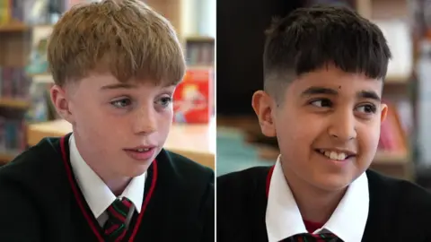 Side-by-side images of two boys in school uniform in different places in a library. One has short blonde hair and freckles. The other has short black hair. Both are looking past the camera and smiling.
