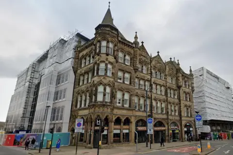 A view of the the Estate Buildings from street level. The building is four-storey's tall and has several spires on its roof.