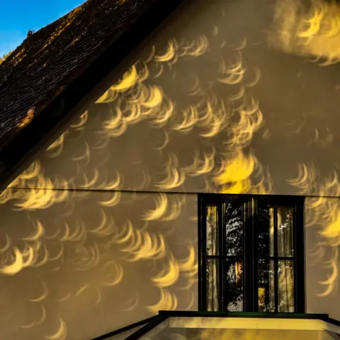 Naturesart Crescent shapes are cast against the outside wall of a house.
