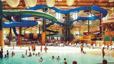 Great Lakes UK Ltd A large warehouse-like indoor space with covered slides towering over a shallow pool
