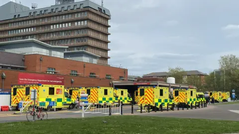 Around nine ambulances are seen queuing up outside the A&E department at Gloucestershire Royal Hospital on a clear day