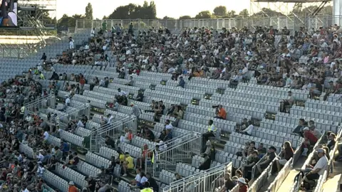 Chris Brown A photo of stands at a stadium. There are empty seats which are grey. You can also see fans sitting in different rows. 