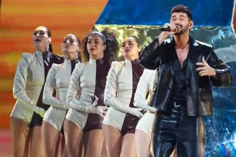 EPA Noam Bettan performs at the Eurovision Song Contest. He is dressed head-to-toe in leather while five female dancers in black and white costumes line up behind him.