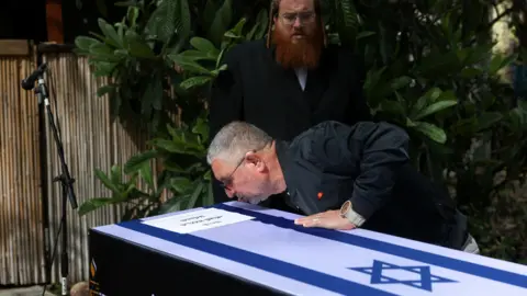 Reuters Danny Elgarat kisses the coffin of his brother, Itzik Elgarat, who died in captivity in Gaza after being kidnapped during Hamas’s 7 October 2023 attack on Israel, during his funeral in Kibbutz Nir Oz, Israel (3 March 2025)