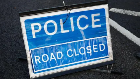 A blue and white sign with the words police, road closed.