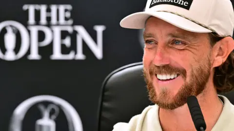 Tommy Fleetwood smiling while speaking at a news conference before the 154th Open Championship at Royal Birkdale