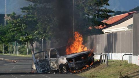 A car is seen burning amid riots in the French territory of New Caledonia