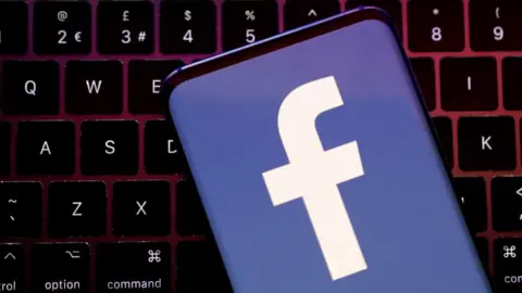 A phone screen showing a Facebook logo against a QWERTY keyboard