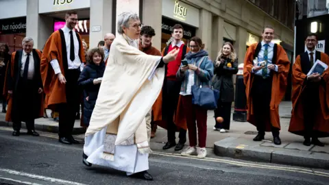 PA Media Clergy member rolls egg