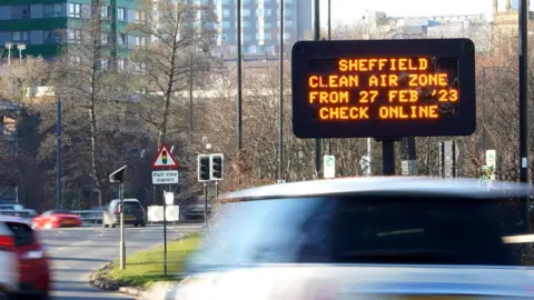 BBC Cars driving past an electronic sign