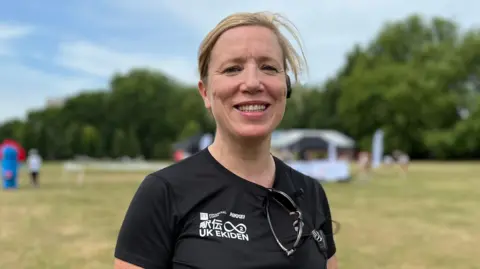 Anna is smiling wearing a black t-shirt with white writing that says "UK EKIDEN" as well as writing in Japanese.