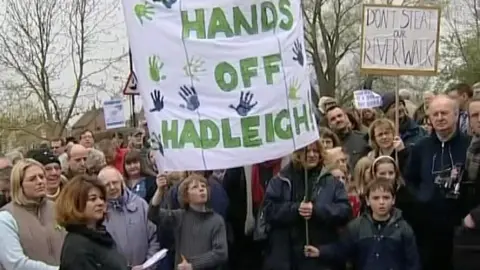 A large crowd dressed in coats holding protest cards