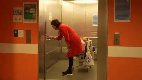 Honor in a lift with the trolley, pushing a button as the door is open.