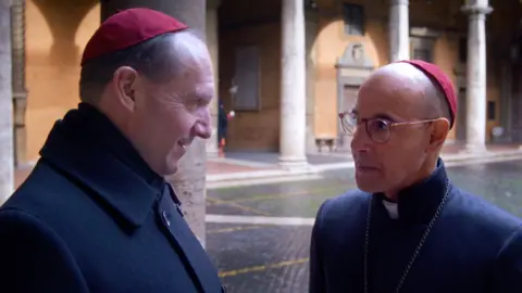 Focus Features Ralph Fiennes and Stanley Tucci pictured in Conclave - they are deep in conversation in the Vatican city