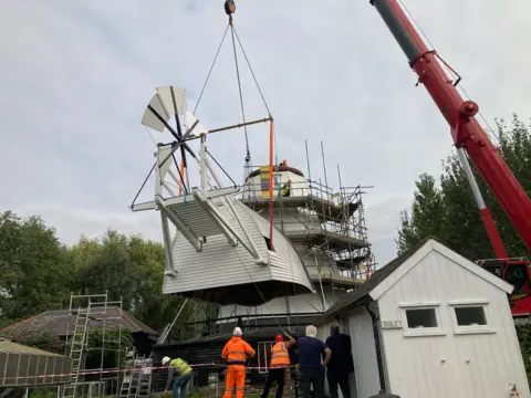 Jo Burn/BBC A crane lifts the 18th Century windmill cap into position