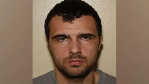 Lancashire Constabulary A police mugshot of Elias Morgan, who has black hair and dark stubble, staring into the camera with a blank expression.