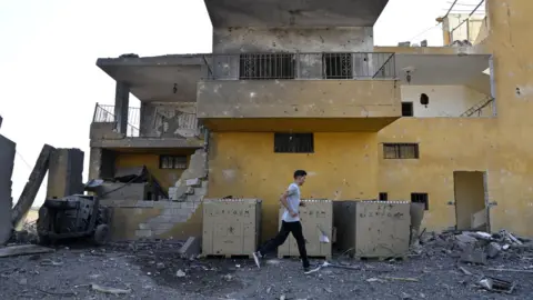 EPA Een man loopt langs een gebouw dat beschadigd is tijdens een gerapporteerde Israëlische luchtaanval in Nabi Sheet, Libanon (21 augustus 2024)