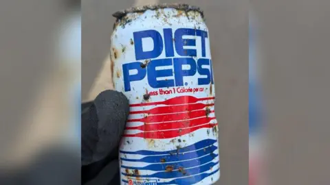 David Martin/Grantham RiverCare Close-up of an old Diet Pepsi can being held up. It has rusty spots all over it with "Diet Pepsi" written in blue and several red and blue lines below. It also says "less than one calorie per can" on the can.