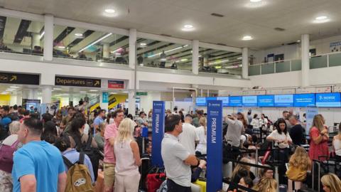 Passengers waiting at Gatwick Airport check in desks