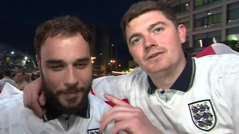 Two men in white kit shirts - one looking slightly disorientated and the other pointing with assertion - as they discuss their predictions for England.