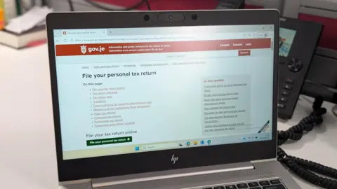 A picture of a laptop screen with the web page for tax returns visible on it. 