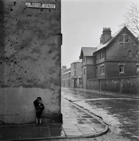 Bert Hardy/Getty Images A small boy standing on the corner of Gladstone Street