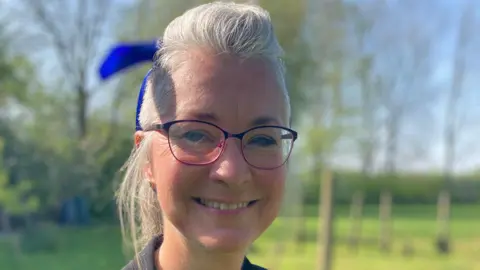 A headteacher smiles into the camera. 