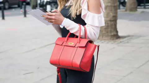 Getty Images Close up image of a woman holding a red Mulberry Bayswater bag