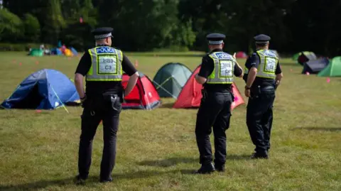 Getty Images/Carl Court Three TVP officers on patrol, standing in front of tents 