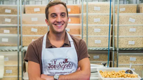 Joe & Save Popcorn Adam Sofer, mede-oprichter en CEO van Joe & Save Popcorn, zit voor een selectie popcorncontainers