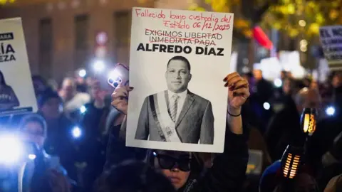 Reuters A demonstrator holds a sign with an image of Alfredo Diaz, a middle-aged man wearing a suit 