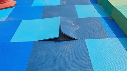 A couple of blue floor tiles stick up above the surface with a cone in the background.