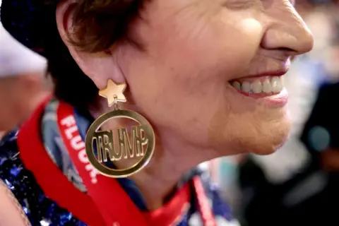 A woman wears an earring dawning Donald Trump's name 