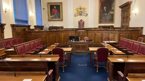 BBC Guernsey's Royal Court with burgundy chairs and brown desks in a courtroom set-up. 