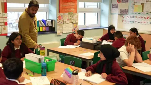 BBC A teacher in a classroom with children