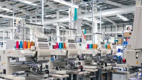 Printful An indoor facility including mainly light-coloured equipment. Nobody is on this photo, which includes silver beams near the ceiling. 